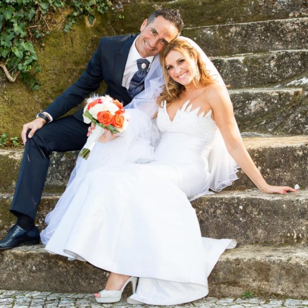 Casal de noivos radiantes e apaixonados compartilham um momento íntimo, vestidos elegantemente em trajes de casamento, com olhares de amor e felicidade em um belo cenário que celebra seu compromisso.
